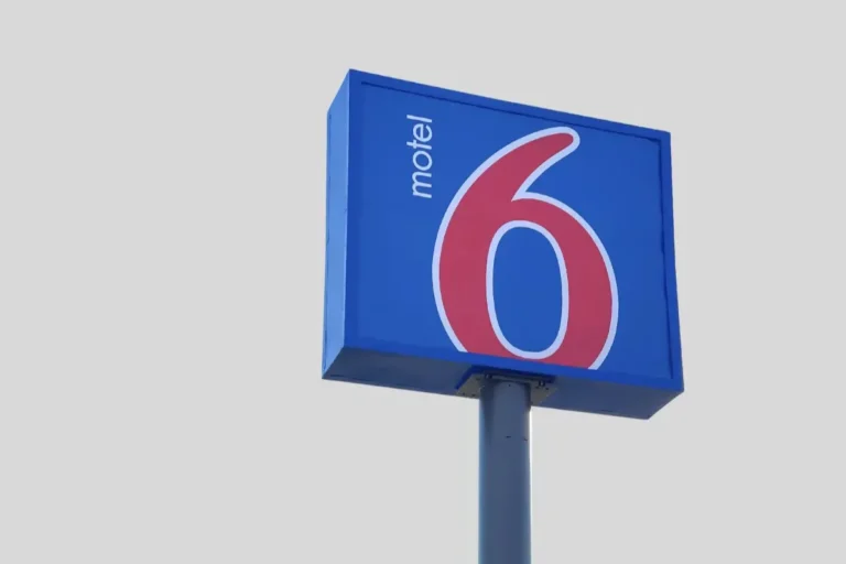 Blue Motel 6 sign with a large red number 6, mounted on a pole against a plain background.