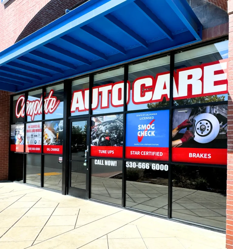 Auto care shop storefront with large window decals advertising services like smog check, oil change, brakes, and tune-ups.